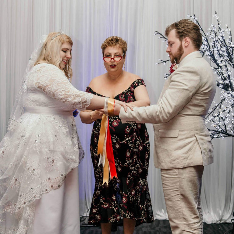 Josie leading a handfasting ceremony for a bride and groom